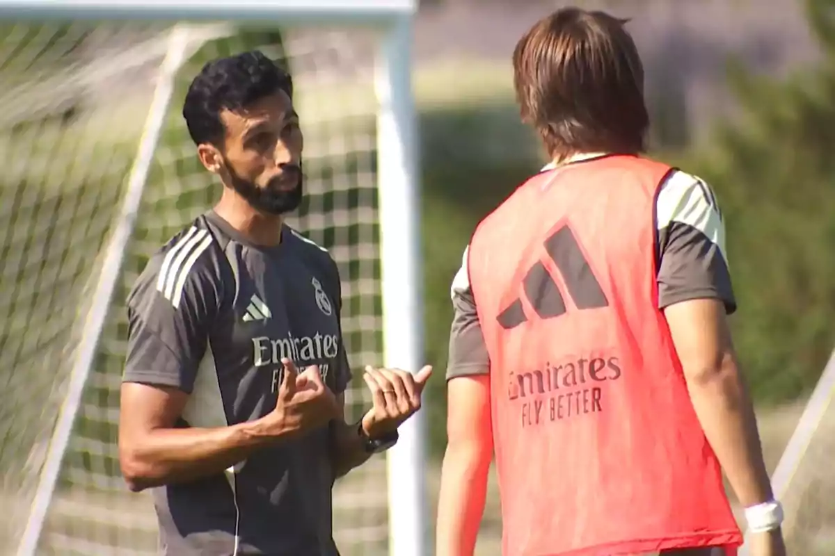 Entrenador de fútbol hablando con un jugador durante una práctica en el campo