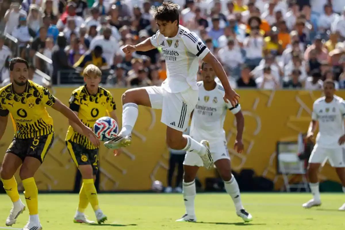 Un jugador del Real Madrid controla el balón en el aire durante un partido contra el Borussia Dortmund mientras varios jugadores observan la jugada en el campo.