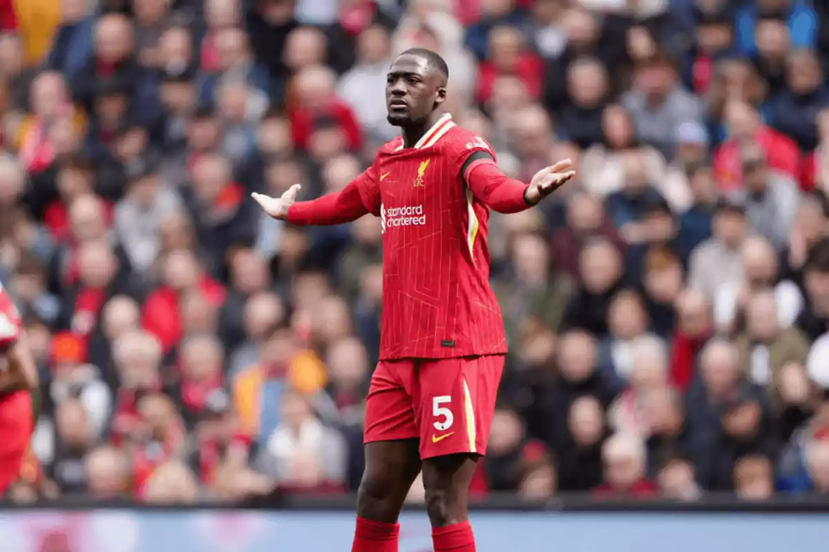 Futbolista del Liverpool con el número 5 en el uniforme rojo levantando los brazos en medio de un partido con el público de fondo