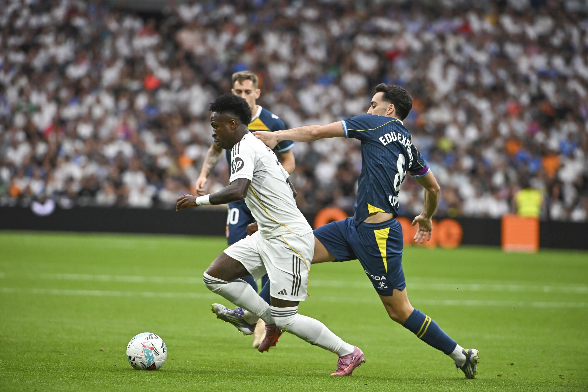 MADRID, 20/09/2025.- El delantero brasilero del Real Madrid Vinícius Jr (izda) pelea por el balón con el jugador del RCD Espanyol Edu Expósito, durante el partido de la jornada 5 de LaLiga EA Sports, que disputan el Real Madrid y el RCD Espanyol, en el estadio Santiago Bernabéu de la capital española. EFE/Fernando VILLAR