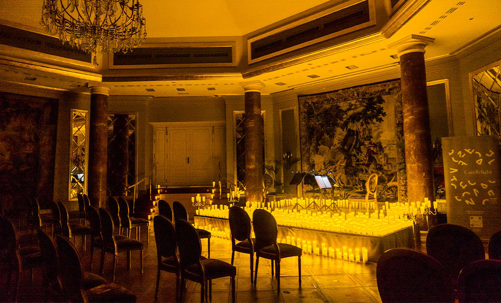 Interior del hotel Wellington, donde un escenario está cubierto de cálidas velas, preparado para un concierto Candlelight.