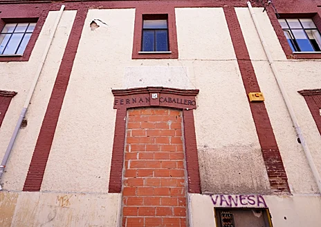 Imagen secundaria 1 - Vista general de la finca, con parte de la fachada del edificio cubierta con redes de protección contra desprendimientos; en las fotos inferiores, la puerta principal del viejo Fernán Caballero y la puerta del vallado forzada días atrás por los okupas