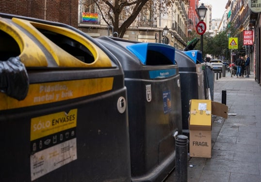 Una caja de cartón abandonada a los pies de los cubos
